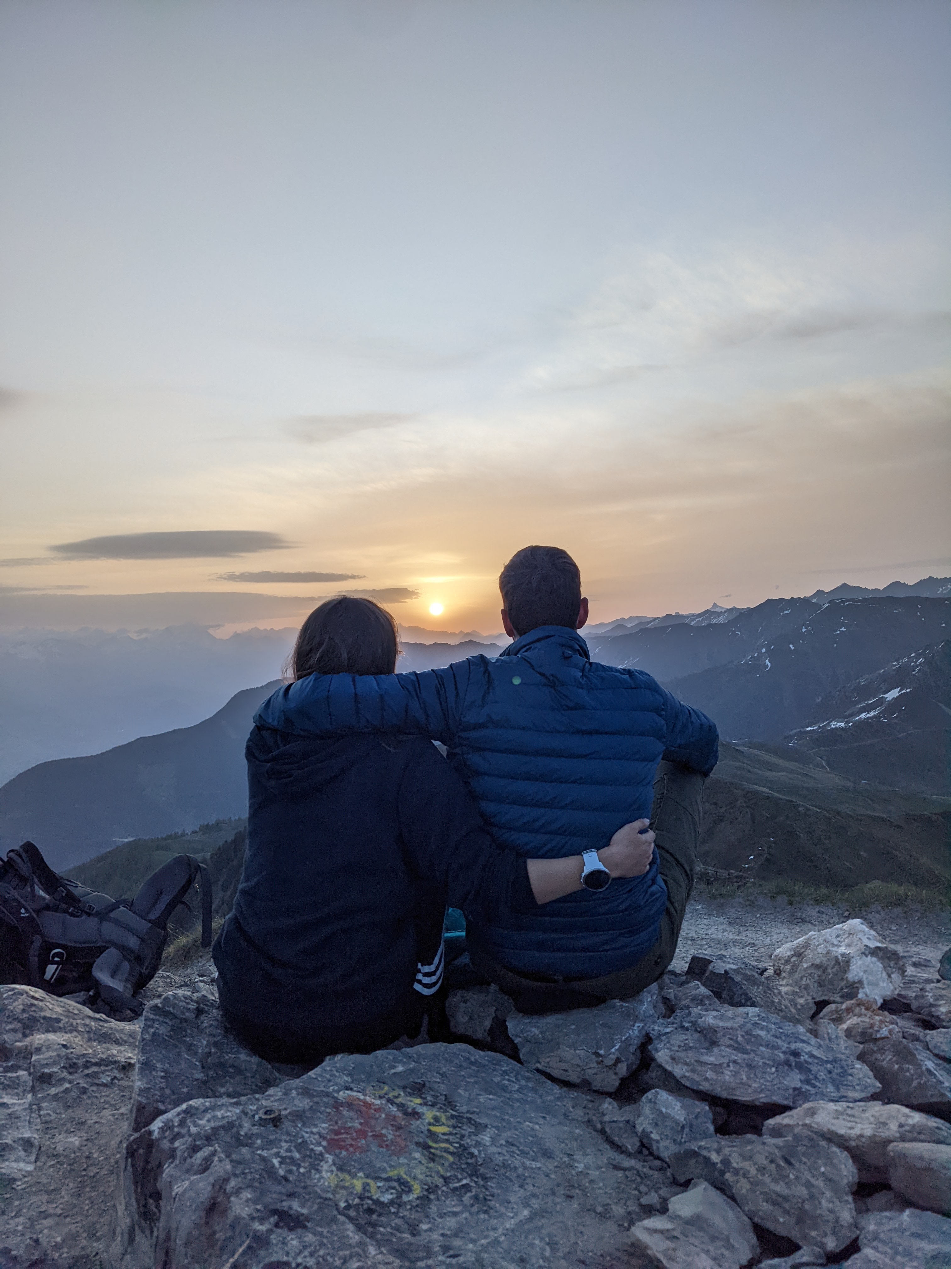 couple assis de dos qui regarde dans la même direction le lever de soleil