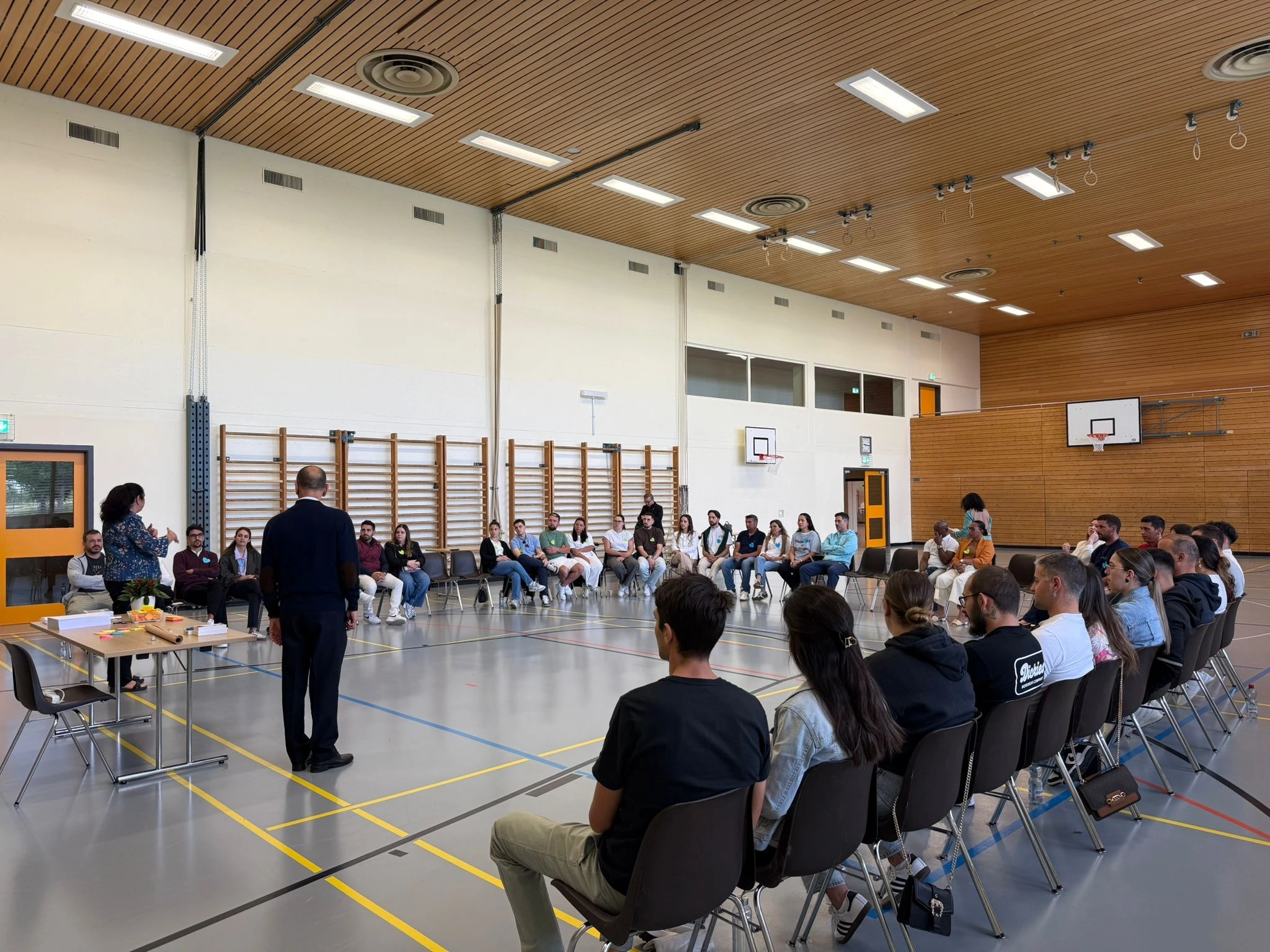 Vingt-trois couples de la communauté catholique lusophone participent à une journée de préparation au mariage dans une salle de sport à Tolochenaz, réunis en cercle autour des animateurs.